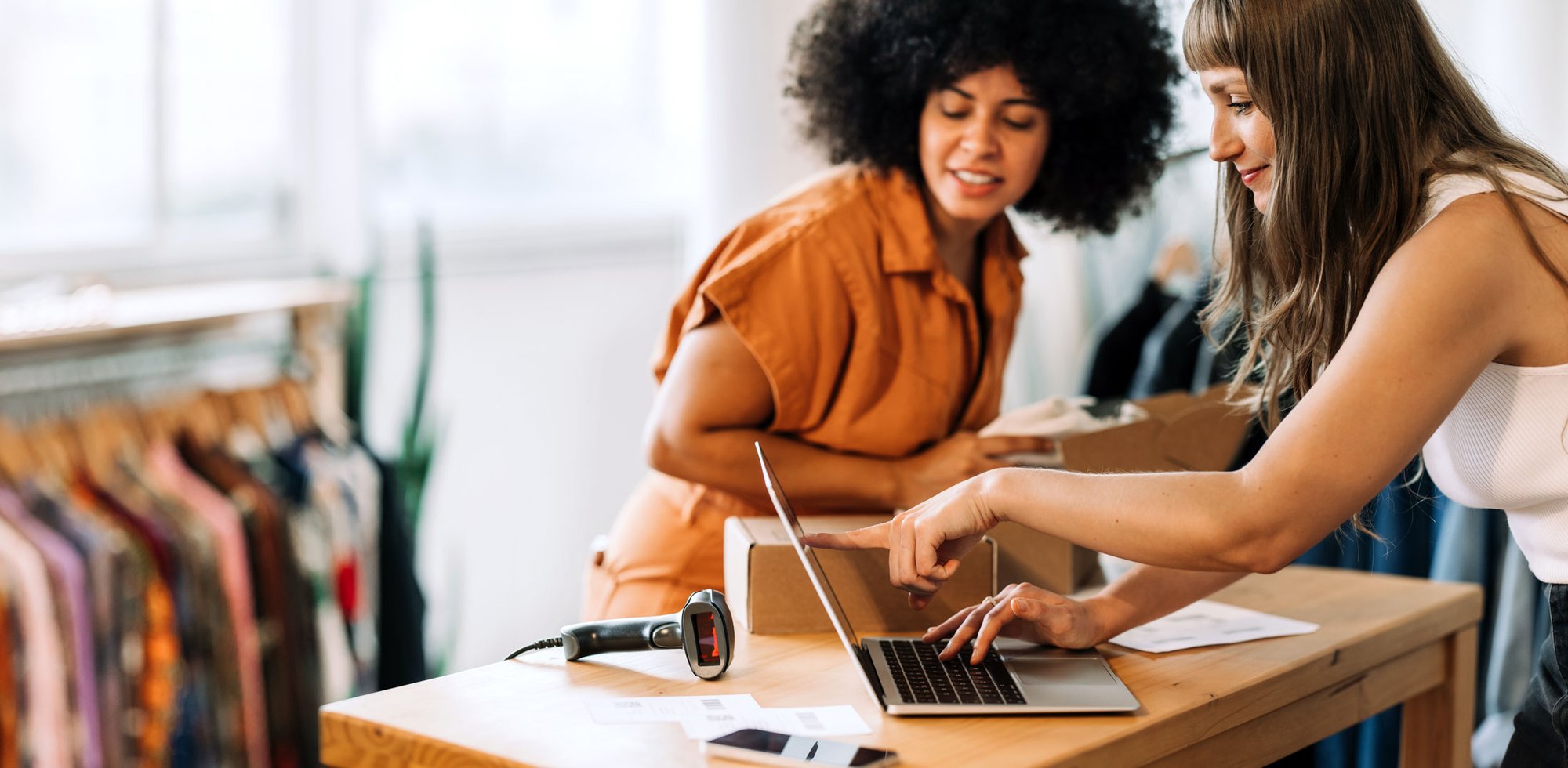 Two Female Business Owners Looking-Laptop-Instore